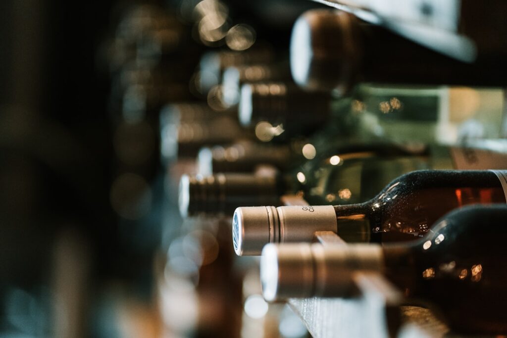 Premium wine bottles stored horizontally in a wine cellar rack with warm bokeh lighting