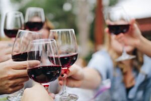Friends toasting with red wine glasses at an outdoor gathering