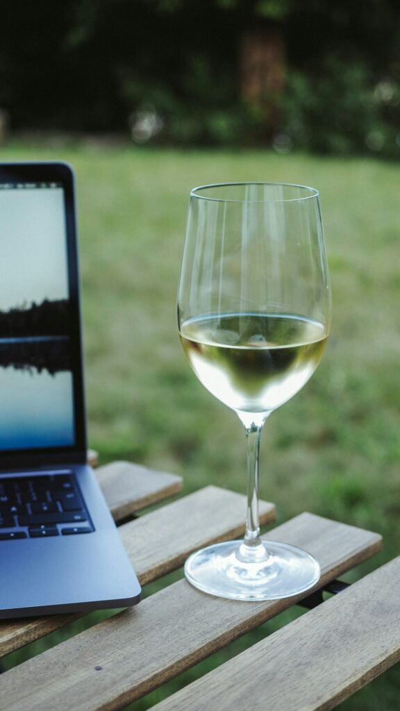 Laptop with analytics data beside a wine glass representing data-driven winery decision making