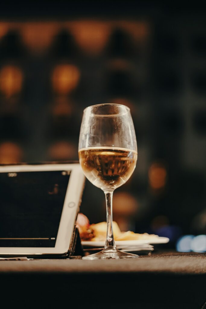 Glass of wine beside tablet showing data on wooden table