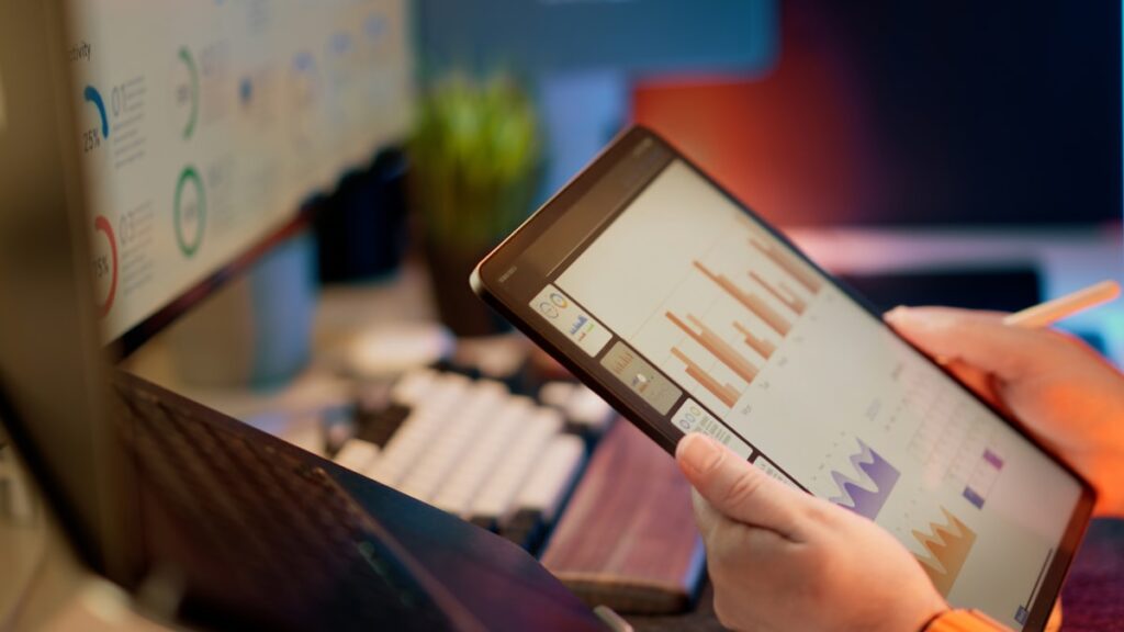 Hand analyzing financial data charts on tablet screen