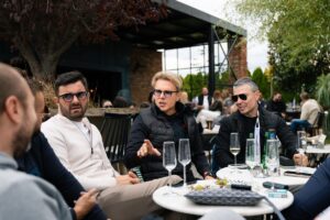 Group of people sitting together at outdoor cafe sharing wine