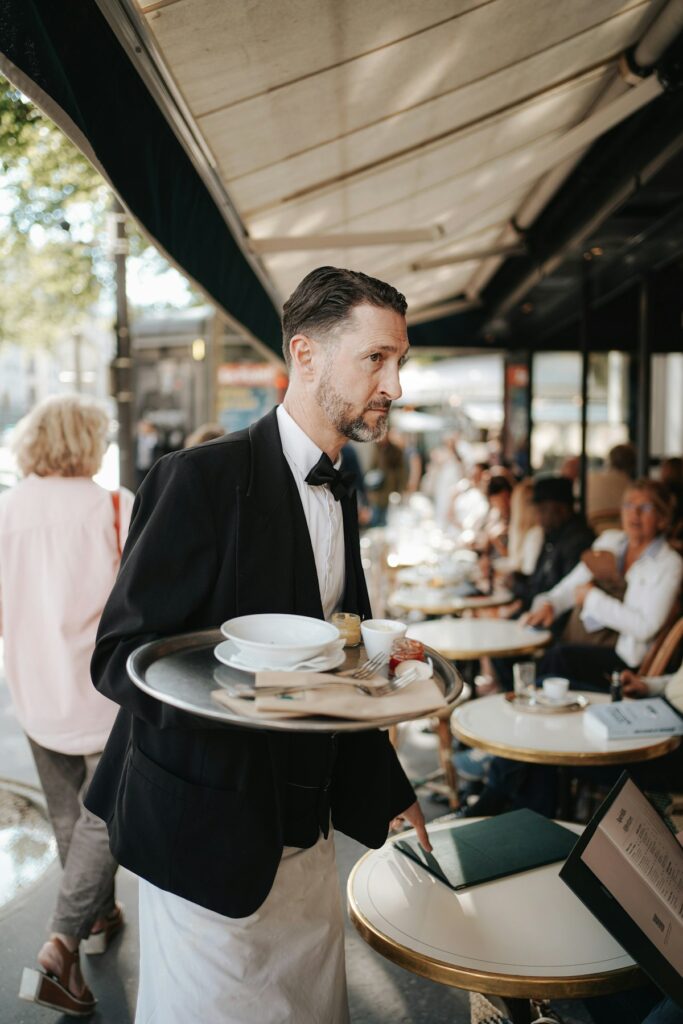 Attentive waiter in tuxedo carrying serving tray