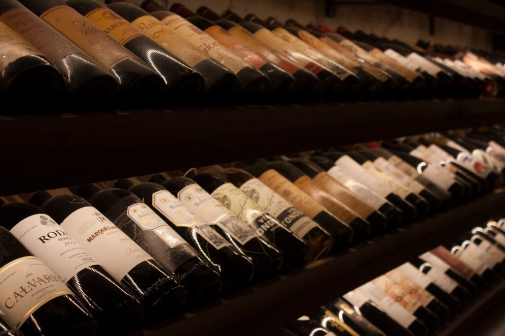 Black and white wine bottles displayed on brown wooden cellar shelf