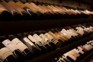 Black and white wine bottles displayed on brown wooden cellar shelf