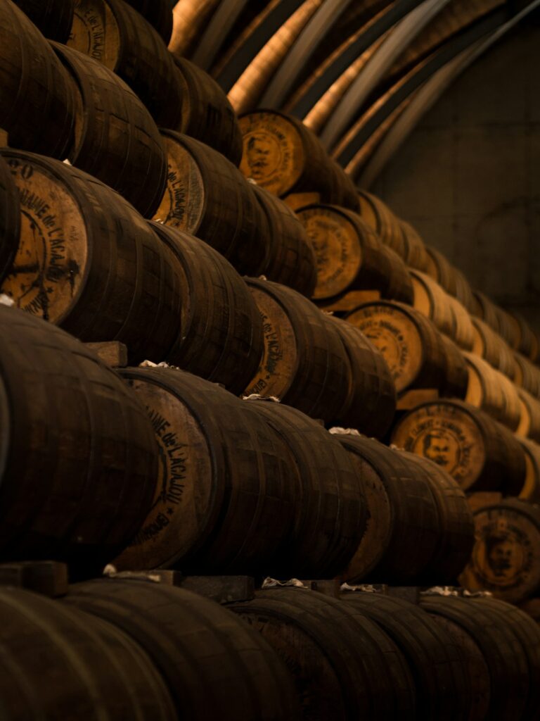 Low light photography of stacked wooden wine barrels in cellar