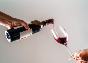 A person pouring wine into another person's glass at a winery tasting
